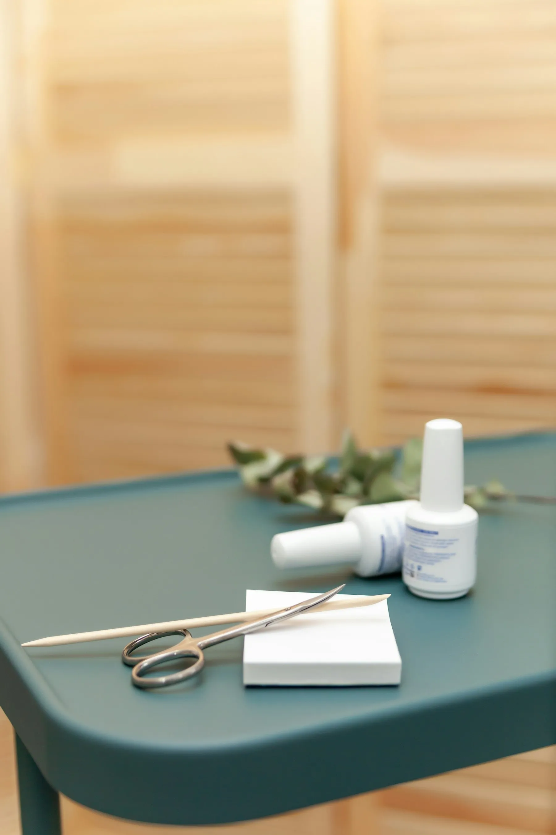 A manicure table with scissors, a buffer and two bottles