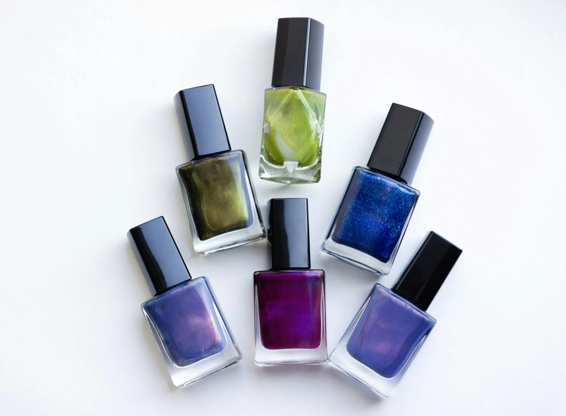Six bottles of nail polish in deep blues and purples